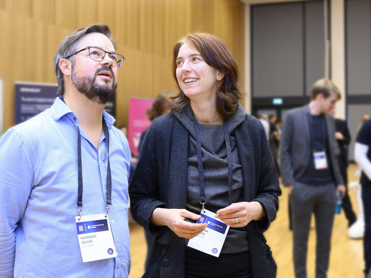 Milena und Norbert nebeneinander stehend bei einer Konferenz
