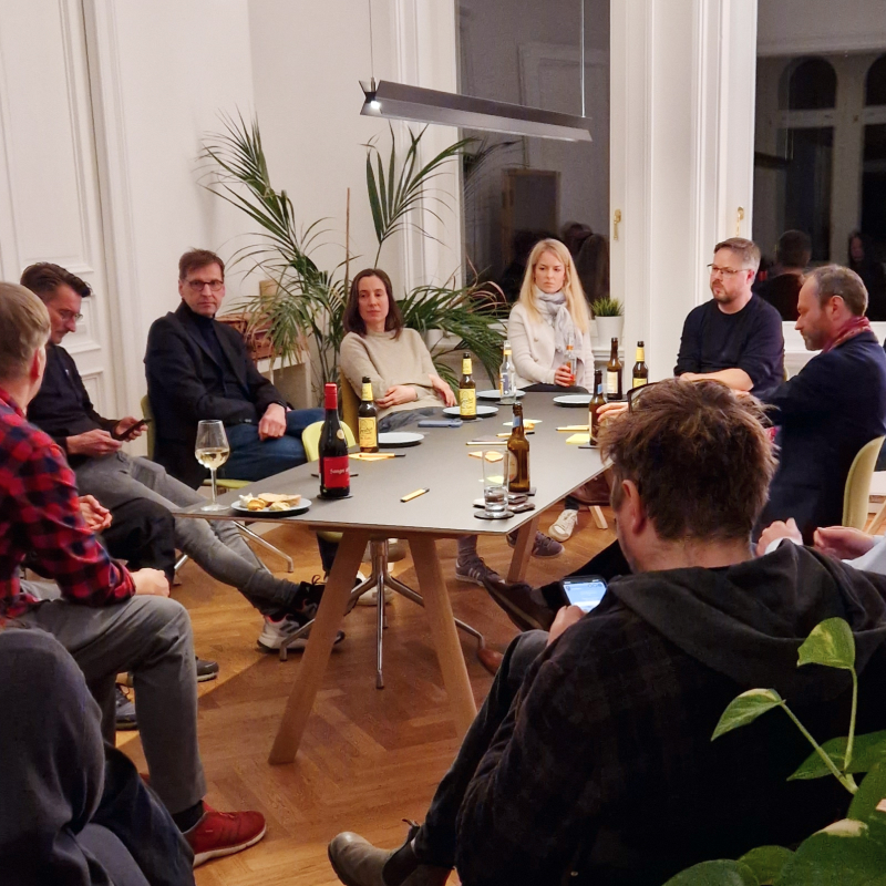 Gäste in der Agentur diskutieren um einen Tisch