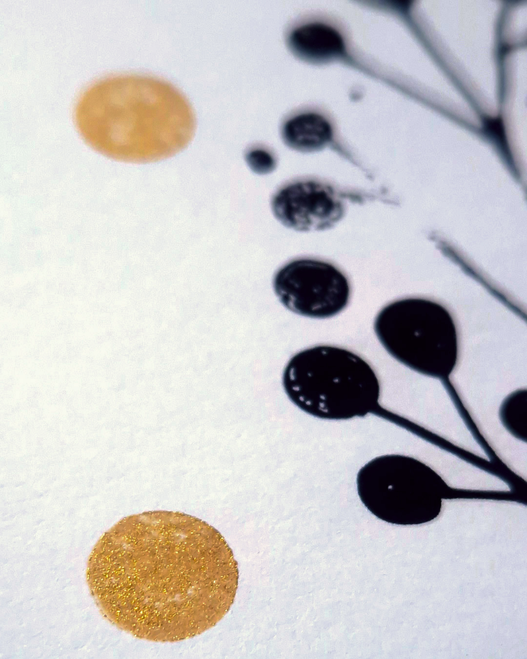 Detail einer Weihnachtskarte mit schwarzen und goldenen Punkten sowie Pflanzenmotiv