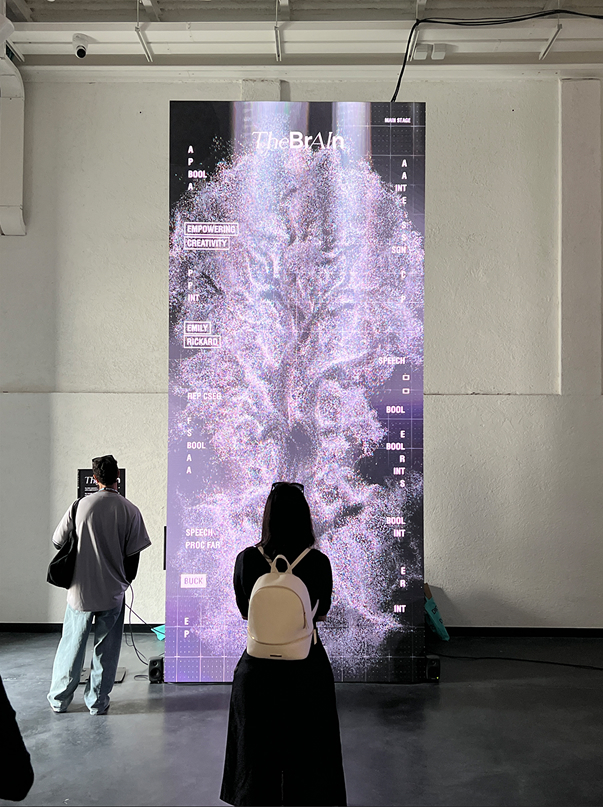 Zwei Personen vor einem hohen, vertikalen Screen mit abstrakter Visualisierung