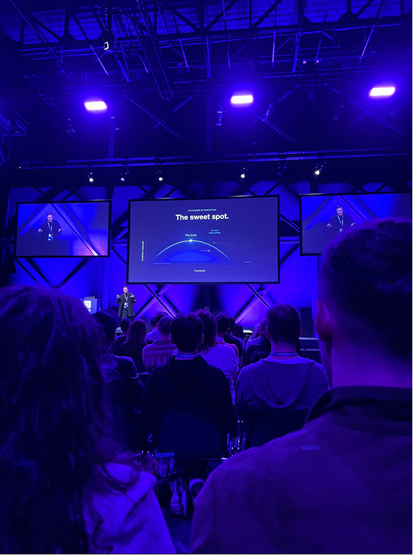 Weitwinkelaufnahme des Publikums in der Halle mit Bühne und Screens
