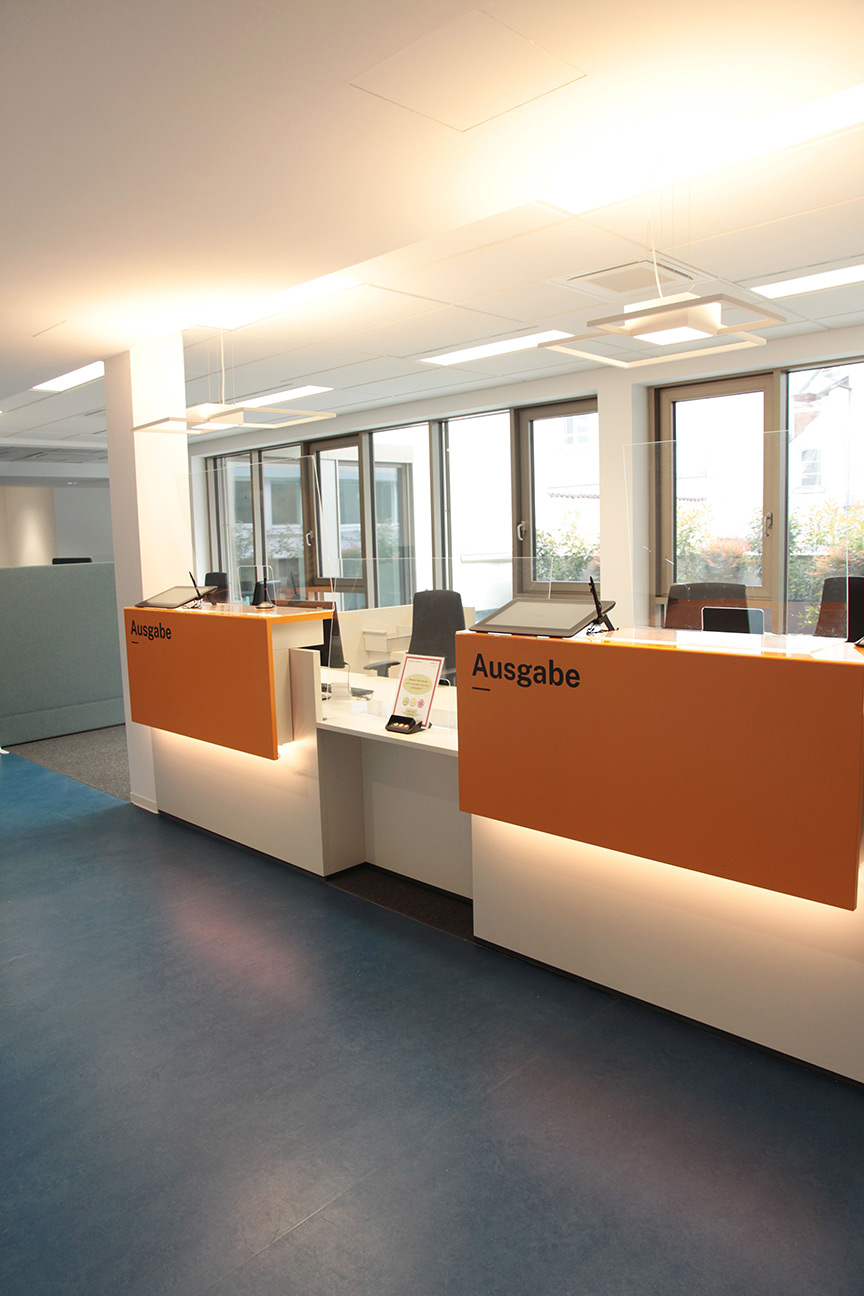 Ausgabeschalter mit orangefarbenen Fronten und Glasabtrennung