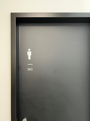 Tür mit WC-Symbol auf einer grauen Oberfläche